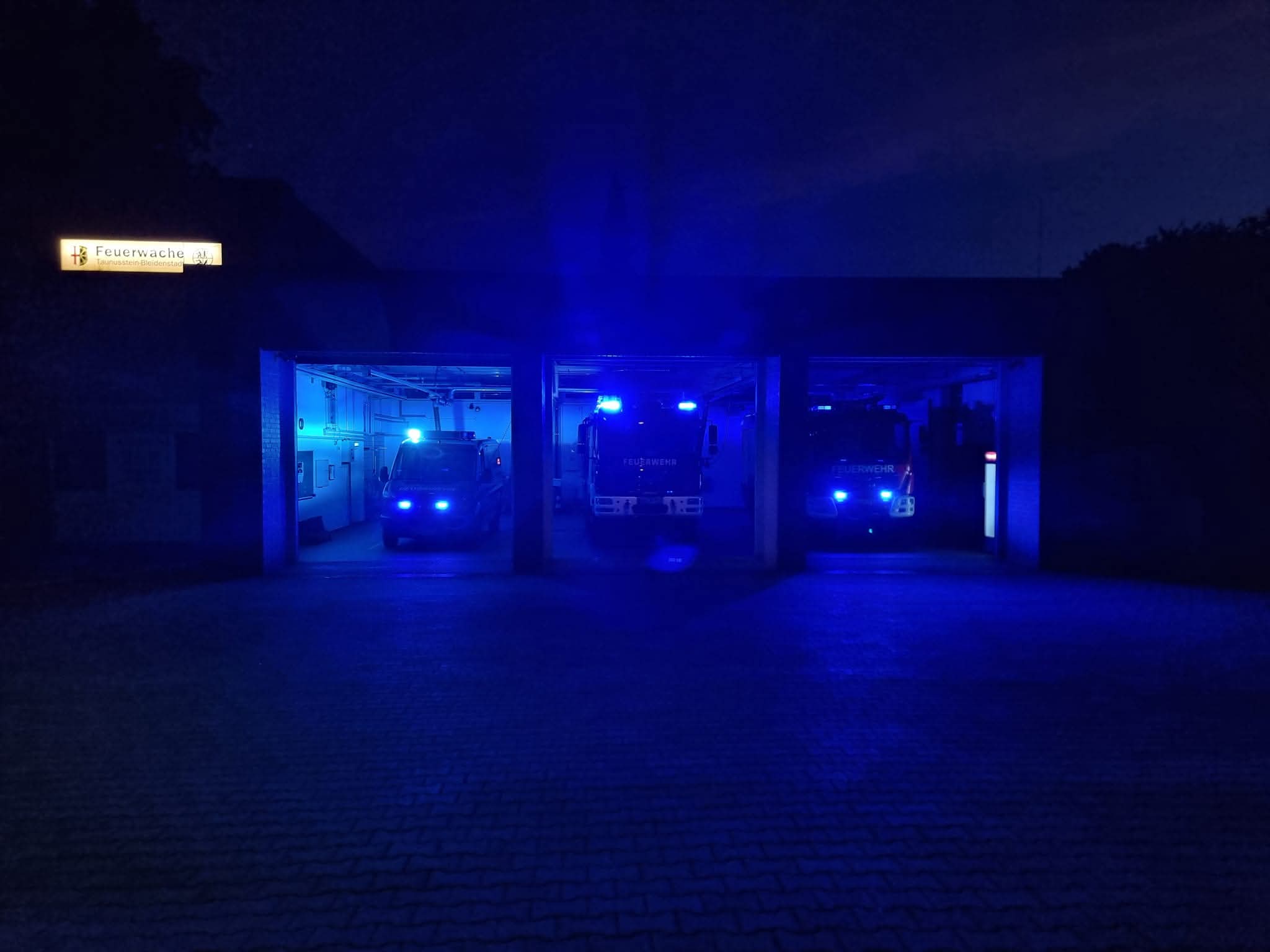 Gerätehaus mit Fahrzeugen bei Nacht und angeschaltetem Blaulicht